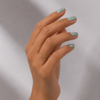 Hand with light green nail polish on a neutral background