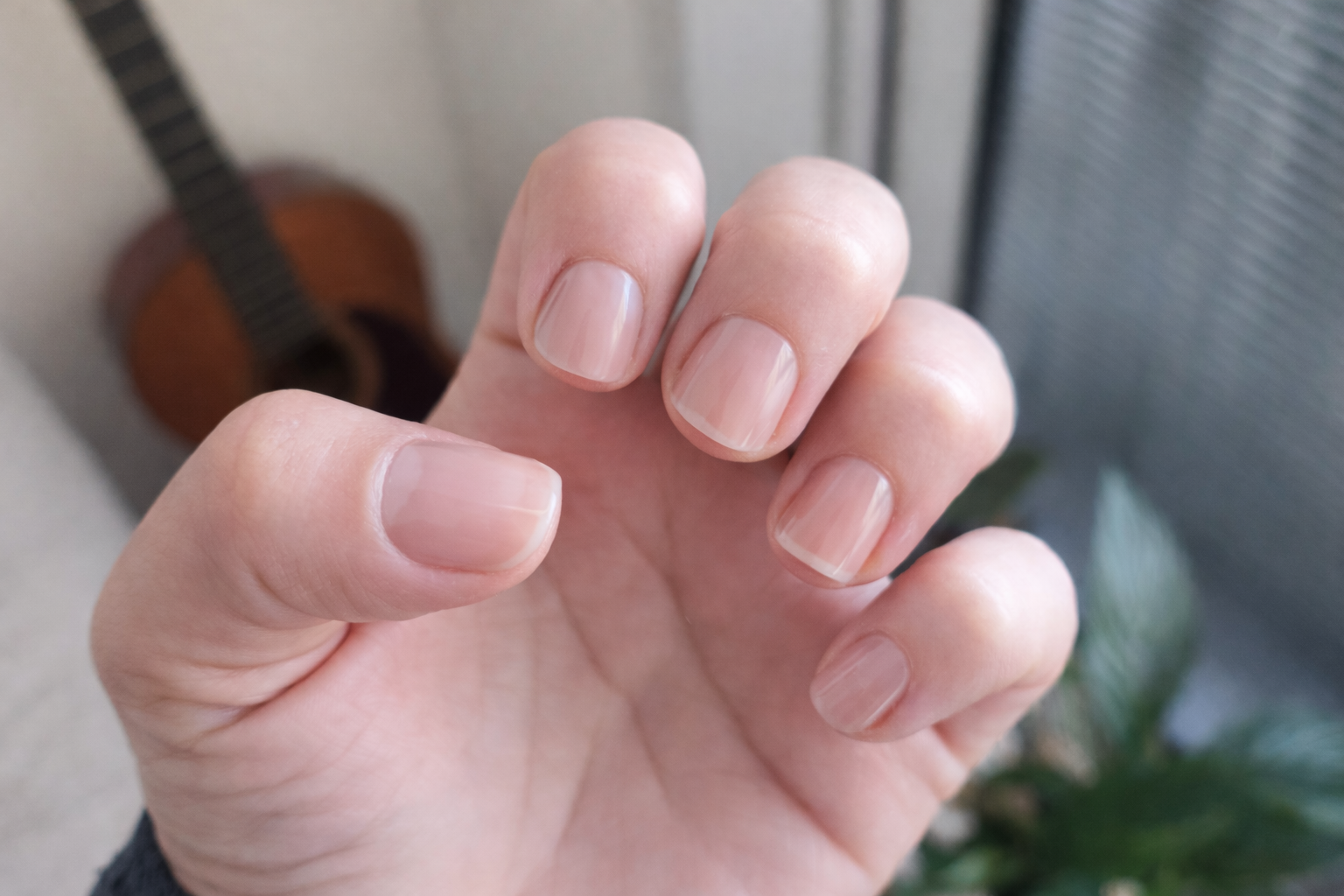 Close-up of a hand with neatly manicured nails in a blurred indoor setting